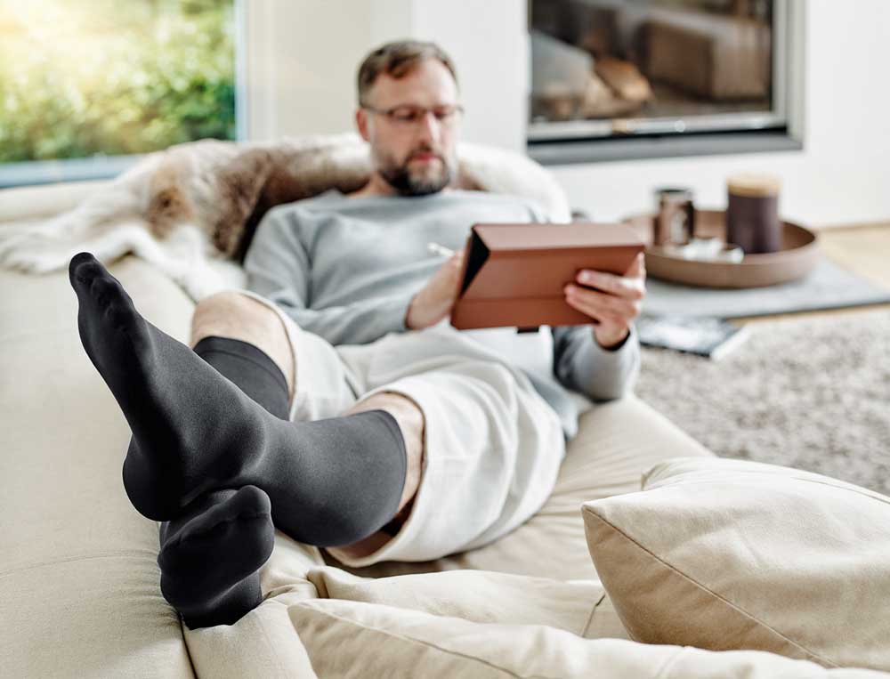 Mann mit Venenstrümpfen auf dem Sofa